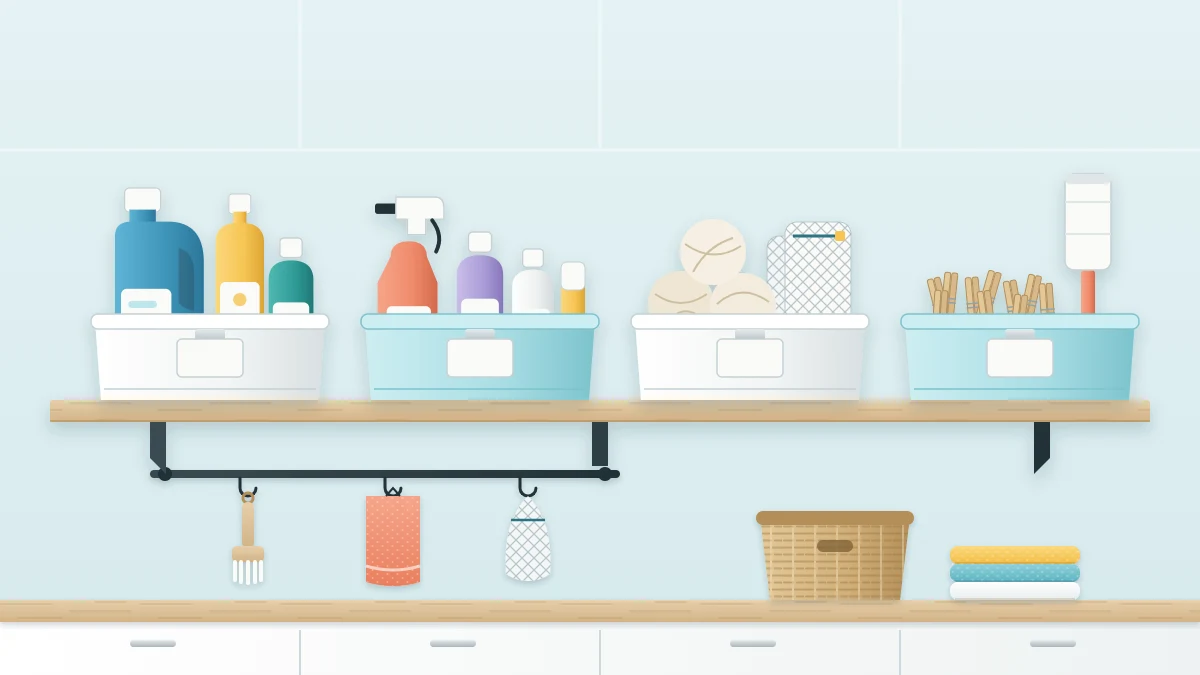 Wooden shelf with four low open bins holding detergent bottles, stain-treatment bottles, dryer balls with mesh bags, and clothespins with a lint roller